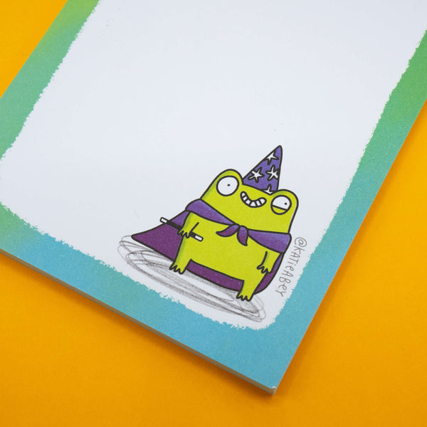 Katie Abey quirky frog pad with rainbow text “None Of My To Do List Is Done But I Certainly Am.” Features a fun wizard frog character at the bottom. Unique funny stationery gift to brighten up your desk and to-do lists.