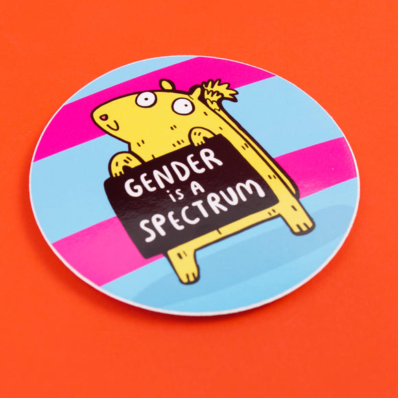 A sticker with pink and blue stripes with a gerbil holding up a sign that says gender is a spectrum.