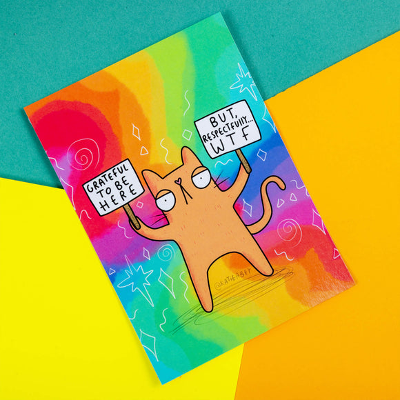 A rainbow postcard of a ginger cat holding up signs saying Grateful to be here but, respectfully WTF on them. Illustrated by Katie Abey