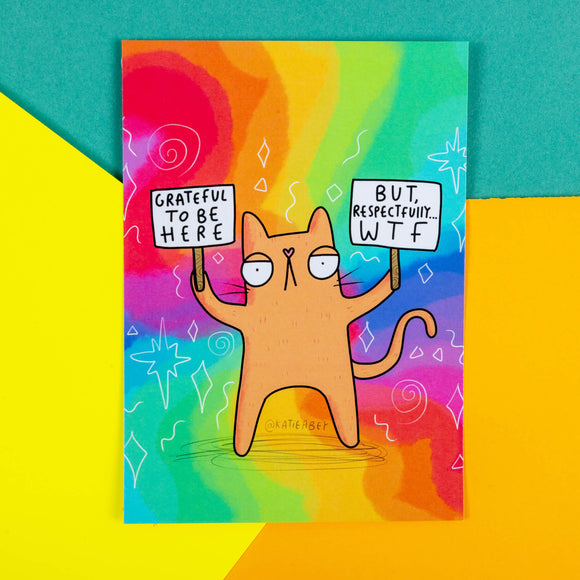 A rainbow postcard of a ginger cat holding up signs saying Grateful to be here but, respectfully WTF on them. Illustrated by Katie Abey