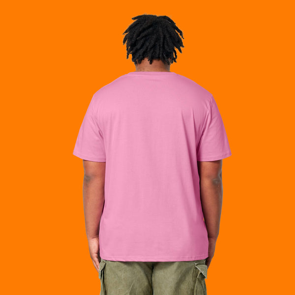 Back view of a model wearing the Katie Abey Grateful To Be Here But Respectfully WTF bubble pink t shirt. Unisex organic cotton graphic tee with classic crew neck and plain back, styled with green trousers against a vibrant orange background.

