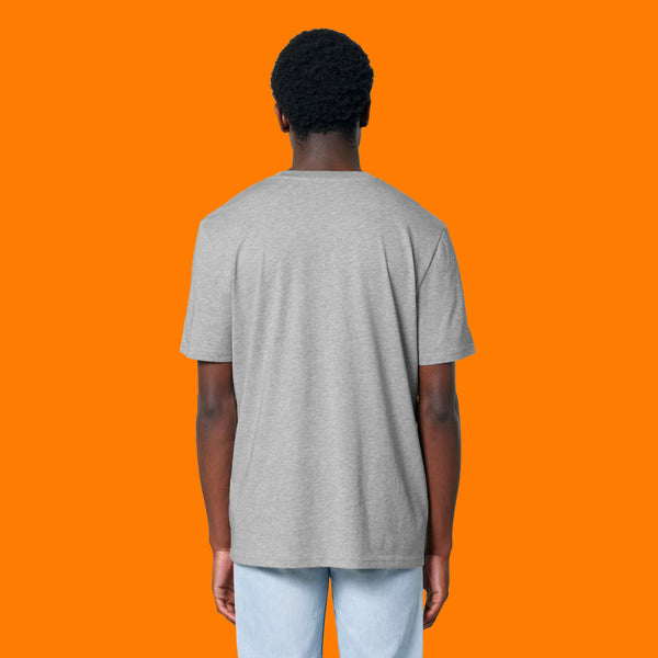 Back view of a model wearing the Katie Abey Grateful To Be Here But Respectfully WTF heather grey graphic t shirt. Unisex organic cotton tee with a relaxed fit and plain back, shown on a model against a bright orange background.
