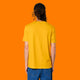 Back view of a model wearing the Katie Abey Grateful To Be Here But Respectfully WTF spectra yellow t shirt. Unisex organic cotton tee with relaxed fit and plain back, styled with jeans against an orange background.
