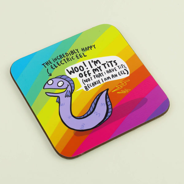 Eel Coaster designed by Katie Abey in the UK. A rounded corner square coaster with a rainbow stripe background with a smiling lilac eel in the middle with a speech bubble reading 'Woo! I'm off my tits (not that I have tits because I am an eel). Near the eels tail is two yellow lightning bolts and text above with an arrow pointing at the eel reading 'The incredibly happy electric eel'. The coaster is laying flat on a white background.