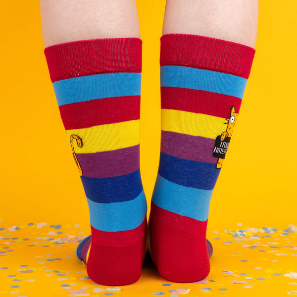 Close-up view of the sock design, showing the orange cat graphic and bold lettering. The colourful rainbow pattern adds a fun twist.