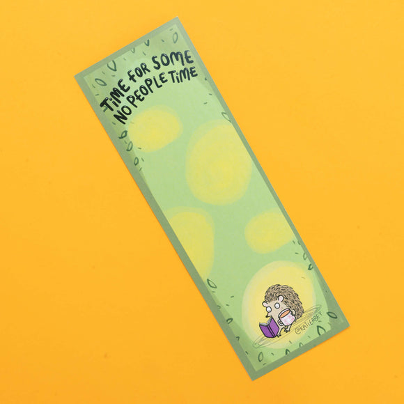 Katie Abey bookmark featuring a small, cartoon hedgehog sitting contentedly, reading a purple book. The bookmark has a soft green background with light yellow spots, and at the top, the phrase 'Time For Some No People Time' is written in playful black lettering. The design is surrounded by a subtle leafy border, perfectly capturing a peaceful, introverted moment