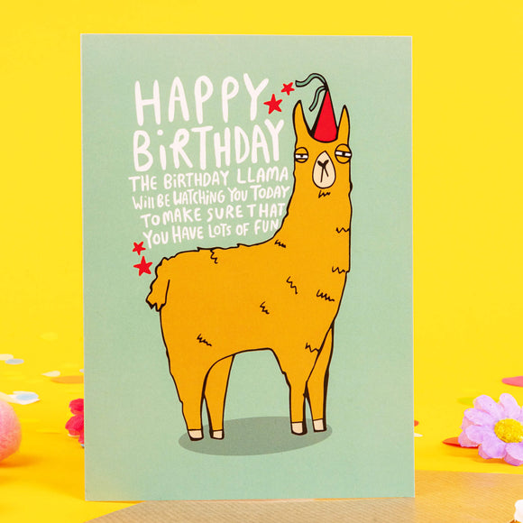 Funny Happy birthday llama A6 greetings card featuring grumpy llama wearing party hat on teal green background. Designed by Katie Abey