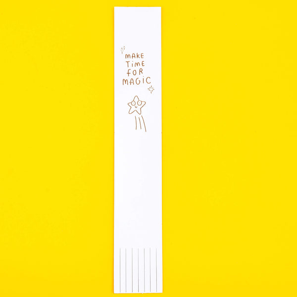 White Leather Bookmark with black writing reads 'Make time for magic' with smiley illustrated star. Designed by Katie Abey in the UK