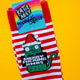 Close up of Katie Abey’s Sweary Cat Merry F*cking Christmas Socks, showing the green cat in a Santa hat on red and white stripes. The colourful Katie Abey Socktopus label is attached. Festive novelty socks by UK illustrator Katie Abey, photographed on a bright yellow background.