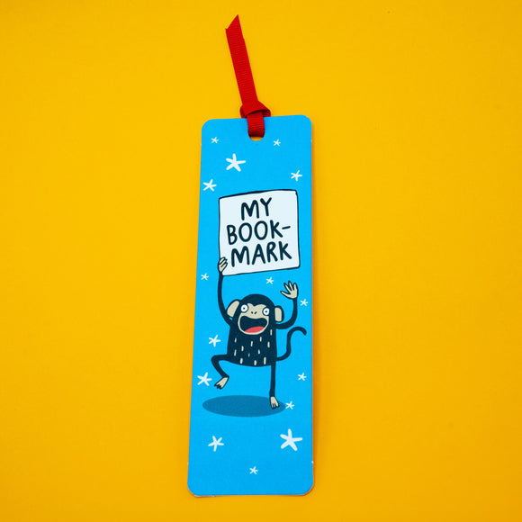 Full view of My Bookmark Monkey bookmark by Katie Abey with red ribbon. Playful monkey illustration on blue starry background holding “My Bookmark” sign. Bright, fun bookmark perfect for book lovers and gifting.