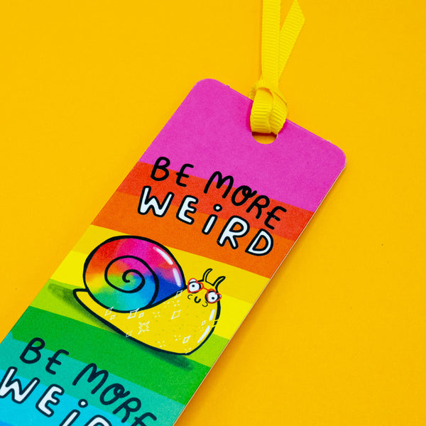 Close-up of Katie Abey Be More Weird Snail Bookmark featuring a rainbow striped background and a cute illustrated snail with glasses. Bright, playful design with bold “Be More Weird” text, celebrating individuality and quirky style.