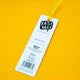 Back view of Katie Abey Be More Weird Snail Bookmark on bright yellow background, showing brand logo, “Be more weird” text and product details. Colourful ribbon loop attached, designed by Katie Abey, an illustrator encouraging individuality and self expression.