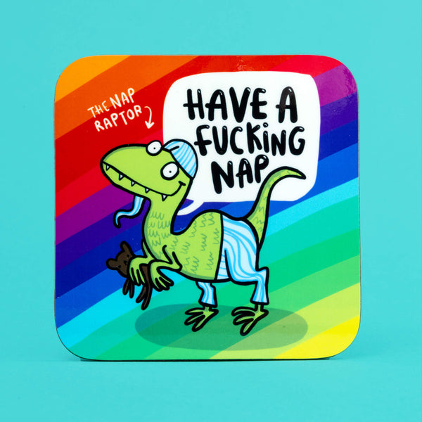 The coaster is a rounded corner square shape with a rainbow stripe background and a green raptor dinosaur smiling wearing pyjamas and holding a teddy bear. There's some text that read the 'The Nap Raptor' with an arrow pointing at the dinosaur and a speech bubble reading 'Have a fucking nap'.