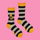 Fun striped socks from Katie Abey with yellow heels, toes, and cuffs, showcasing a cheeky orange cat design holding a "C**T" sign. A playful and bold accessory, perfect for adding a dash of weirdness to your sock drawer or gifting with sass.