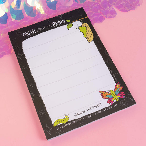 Angled shot of the Katie Abey notepad featuring a vibrant caterpillar-to-butterfly illustration and the motivational phrase “Honour The Mush!” An inspiring tool for personal growth and creativity.