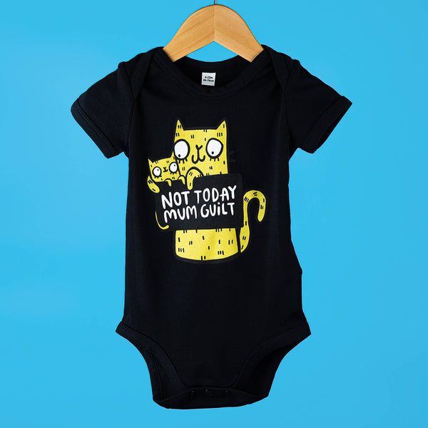 Black baby grow for babies featuring a yellow illustrated cat holding sign that reads 'Not Today Mum Guilt'. Designed by Katie Abey in the UK