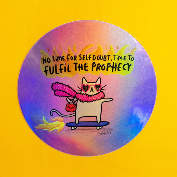 Holographic vinyl sticker by Katie Abey featuring a cat in heart-shaped sunglasses, pink fluffy scarf and handbag riding a skateboard with flames, under the text “No time for self-doubt. Time to fulfil the prophecy.” Shiny rainbow effect finish, approx 8cm, perfect for laptops, water bottles or notebooks.