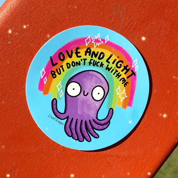 Love and Light but don't fuck with me circular pale blue vinyl sticker, featuring purple smiley octopus with rainbow and stars, and black writing. Designed by Katie Abey in the UK