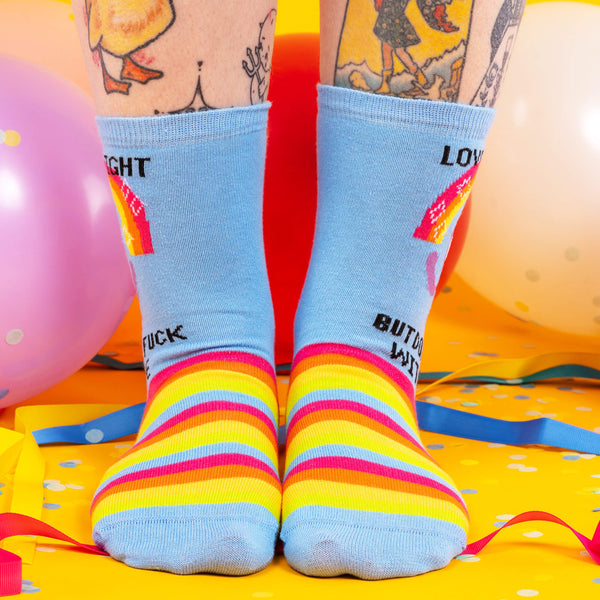 a pair of socks on some feet which are blue with rainbows with an octopus on with text saying love and light but don't fuck with me