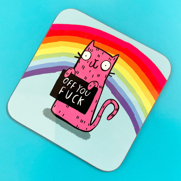 A blue coaster and rainbow coaster with a pink illustrated cat by Katie Abey holding a sign saying 'Off you fuck' it is leaning against a colourful background