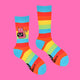 Katie Abey’s rainbow striped socks laid flat, showcasing a pink cat holding a cheeky "Off You F***" sign. Bright, weird, and fun, these socks are perfect for bold, statement-making fashion fans.