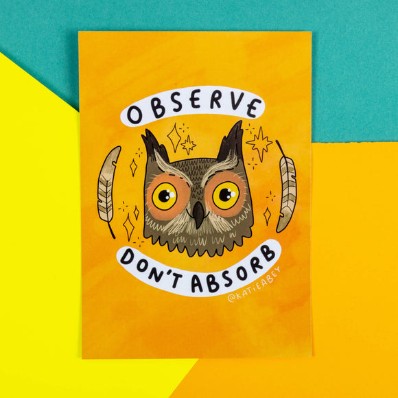An orange postcard with an illustration of an owl with feathers and sparkles around their head with observe and don't absorb written around it.