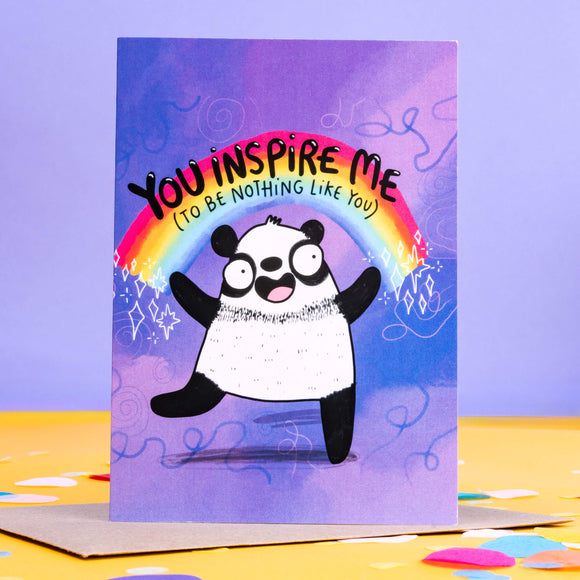 Purple greeting card with panda and rainbow illustration with the words 'you inspire me (to be nothing like you)' written on.