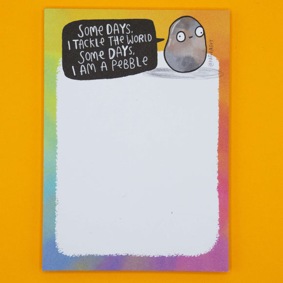 Full view of Katie Abey's "Some Days I Am A Pebble Pad" notepad with rainbow edges and a quirky pebble illustration. Unique stationery pad designed by UK illustrator Katie Abey, perfect for lists, notes, and self-care reminders.