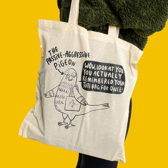 Passive Aggressive Pigeon Tote Bag by Katie Abey shown in full, natural cotton canvas with black illustration and sarcastic slogan. Features a cartoon pigeon holding a tote bag, perfect eco-friendly reusable shopping bag with a playful, alternative design from a UK small business.