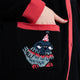 Close up of pocket pigeon illustration on the Katie Abey x Rebel Romance Pigeon Party Long Cardigan. Black longline knit with red cuffs and trim, featuring a cheeky pigeon in a party hat on the front pocket.
