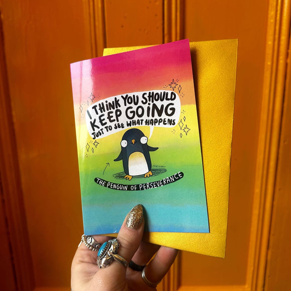 cute rainbow coloured A6 greeting card featuring The Penguin of Perseverance with a smile on it's face and speech bubble above that reads 'I think you should keep going just to see what happens'. The card comes with a gold envelope. Designed by Katie Abey.