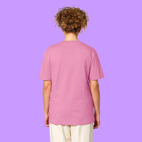 Back view of a Bubble Pink Katie Abey Prioritising Whimsy, Nonsense and Joy adults t-shirt worn by a model with curly hair. The organic cotton unisex graphic tee shows the plain back and relaxed everyday fit.
