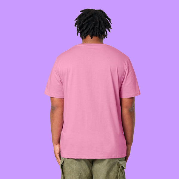 Back view of a Bubble Pink Katie Abey Prioritising Whimsy, Nonsense and Joy adults t-shirt worn by a model with short dreadlocks. The organic cotton unisex tee has a relaxed fit with a plain back, photographed against a purple background.