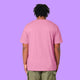 Back view of a Bubble Pink Katie Abey Prioritising Whimsy, Nonsense and Joy adults t-shirt worn by a model with short dreadlocks. The organic cotton unisex tee has a relaxed fit with a plain back, photographed against a purple background.