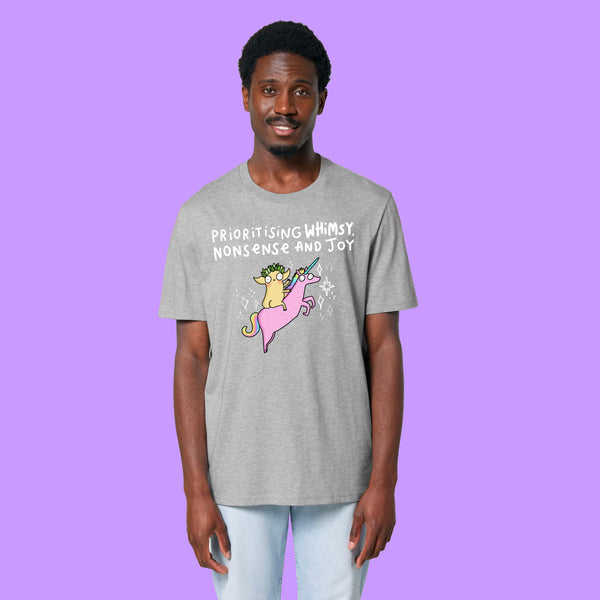 Front view of a heather grey Katie Abey Prioritising Whimsy, Nonsense and Joy adults graphic tee worn by a model. Features a colourful unicorn illustration and fun lettering celebrating joy, nonsense and whimsy.
