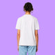 Back view of a white Katie Abey Prioritising Whimsy, Nonsense and Joy adults t-shirt worn by a model against a purple background. The organic cotton unisex tee has a relaxed everyday fit and plain back.
