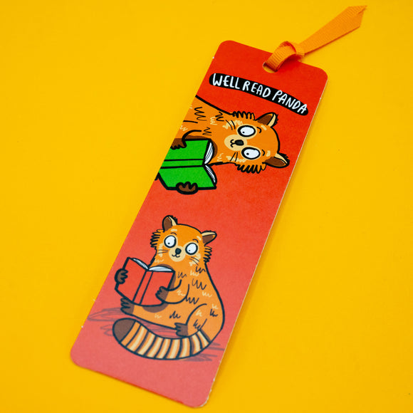 Katie Abey Well Read Panda Red Panda Bookmark laid at an angle on yellow background, showing full design with two red pandas reading books. Bright colourful bookmark with ribbon, perfect gift for readers and stationery lovers.
