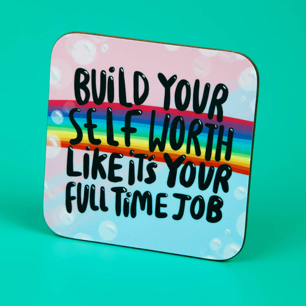A Katie Abey illustrated coaster on a pastel blue and pink bubbly background with a rainbow running through. Over the top text says 'Build your self worth likes its your full time job'