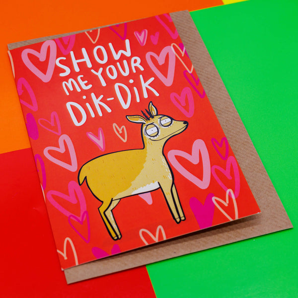A red card with a dik dik with red hearts behind it saying show me your Dik-Dik. It is sat on its envelope on a primary coloured background.