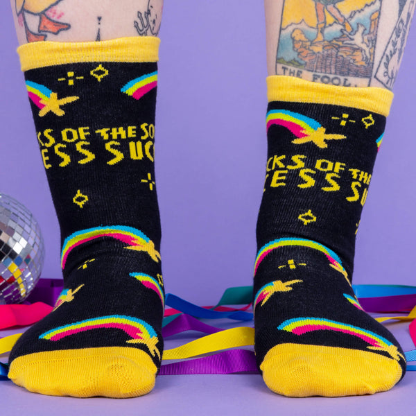 A white model with tattooed legs wearing black socks with yellow heels and band around the top with shooting stars and writing saying the socks of success designed by Katie Abey