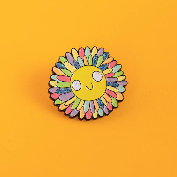 Katie Abey enamel pin showing a happy sun with rainbow and glitter rays. Bright and bold, this pin is a cheerful addition to bags, jackets, and pinboards, made to remind you of the love and kindness in the world.