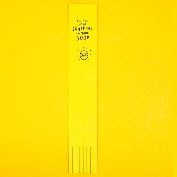 Yellow Leather Bookmark with black writing reads 'A little bit of sunshine in your book' with smiley illustrated sun. Designed by Katie Abey in the UK
