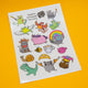 Full sheet of Katie Abey Terrific Temporary Tattoos displayed on a yellow background, packed with cute and quirky illustrated characters including animals, fantasy creatures and humorous designs.