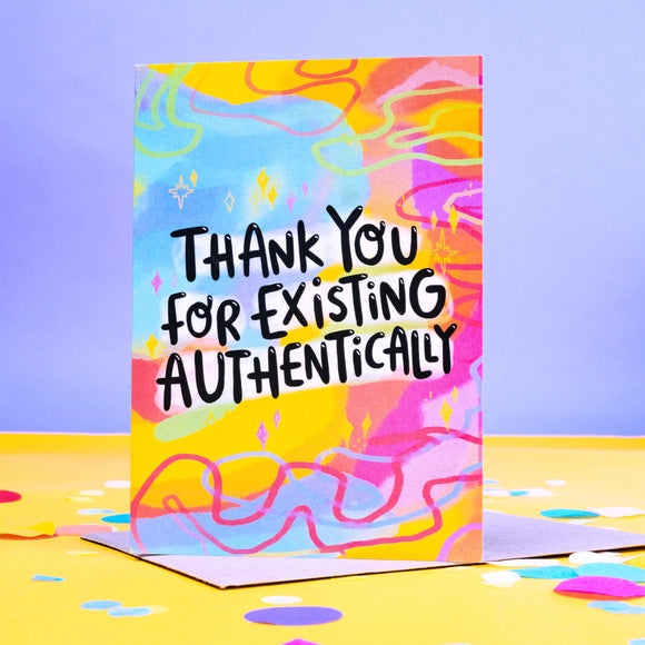 Greeting card with a rainbow coloured background with 'thank you for existing authentically' written on the front in black letters.