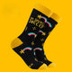 Katie Abey “The Socks of Success” novelty socks shown as a full pair against a bold yellow background. The black socks have yellow accents, bright rainbow motifs, stars, and the cheerful slogan “The Socks of Success”. A fun, colourful and motivational design from UK illustrator Katie Abey encouraging you to embrace your weirdness.