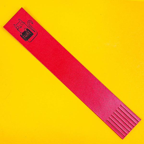 a red bookmark with an embossed cat on the top illustrated by Katie Abey holding a sign saying twat