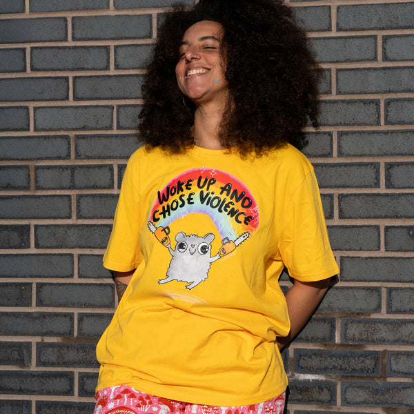 Front view of the Katie Abey Woke Up and Chose Violence Hamster Adults Tee in Spectra Yellow worn casually. The design shows a smiling hamster with chainsaws under a rainbow and bold lettering. Bright yellow unisex t shirt by illustrator Katie Abey, perfect for fans of humour, colour and alternative fashion.
