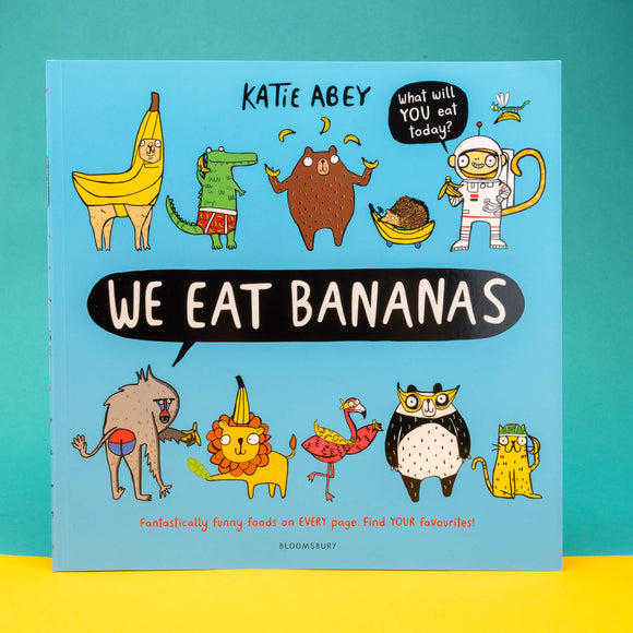 We Eat Bananas book by Katie Abey. The cover is a light blue with various animals wearing or holding bananas with text in the middle reading 'we eat bananas'. One animal has a speech bubble reading 'what will YOU eat today' and bottom text reads 'fantastically funny foods on EVERY page. Find YOUR favourites!' Printed by Bloomsbury.