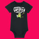 Black organic cotton babygrow featuring Wield Your Weird artwork by Katie Abey. A green illustrated cat holds a sword and shield beneath bold text reading “Wield Your Weird”. Short sleeved baby bodysuit with shoulder snap fastening and bottom poppers, photographed on a bright pink background.