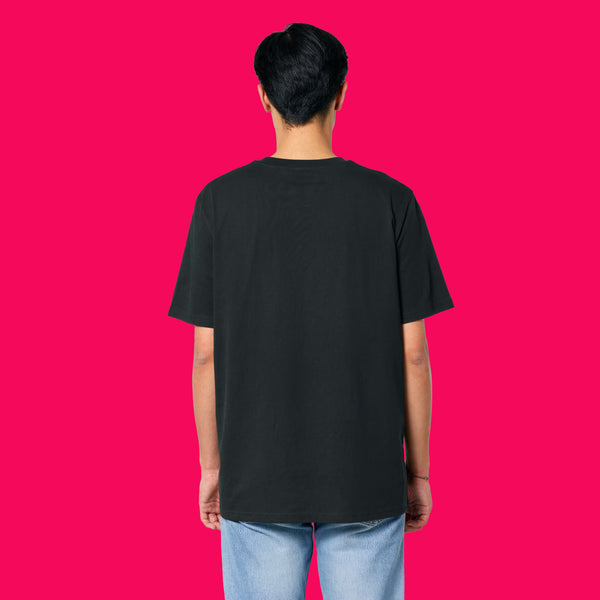 Back view of a model wearing the Wield Your Weird Adults T Shirt by Katie Abey in black. The unisex fit T shirt is shown from behind with light blue jeans, photographed against a bright pink background.